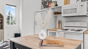 Een keuken met witte apparaten, een houten tafel en een vaas met veertjes.