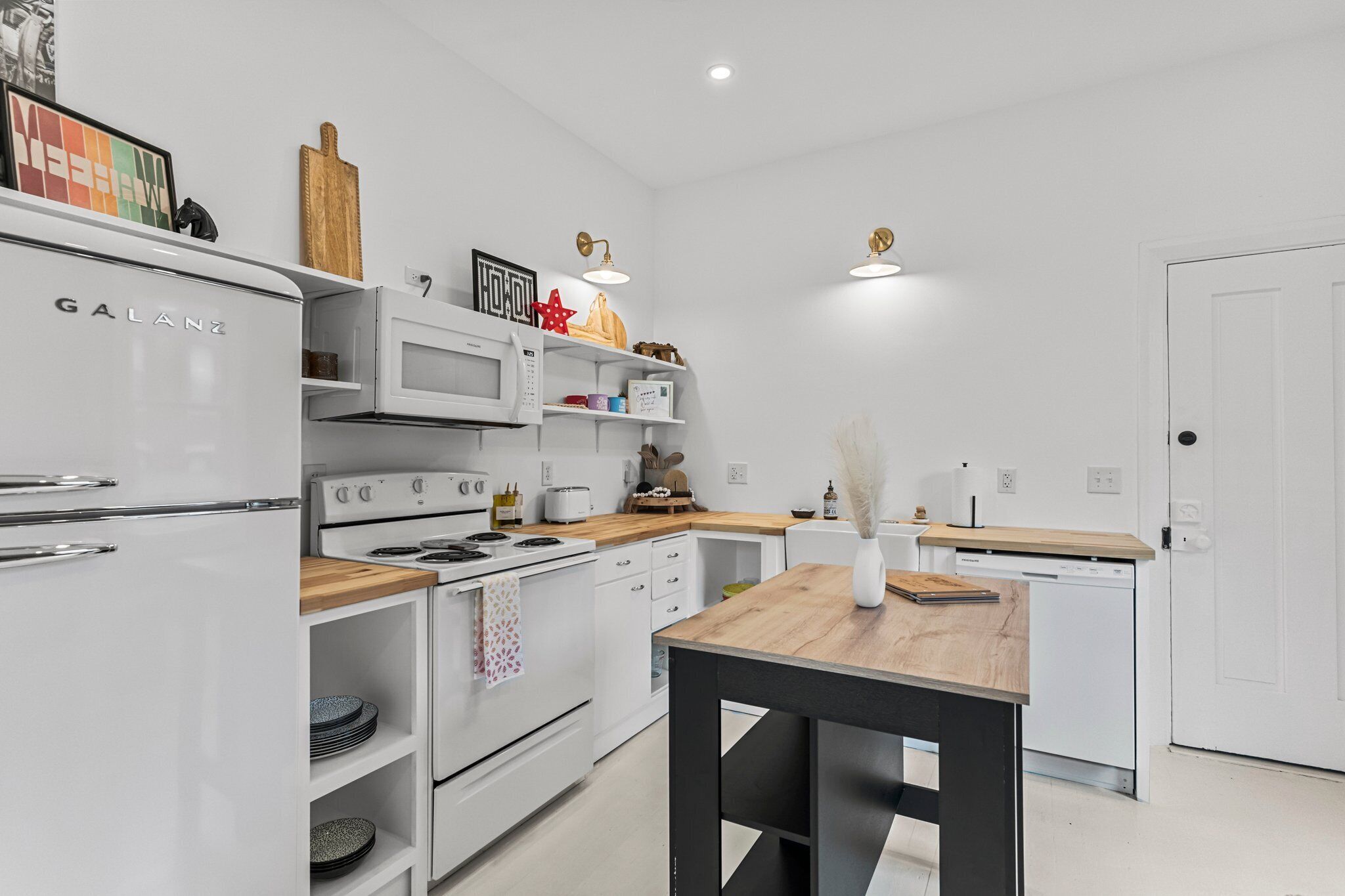 A modern kitchen with white appliances, a wooden countertop, and a black dining table.