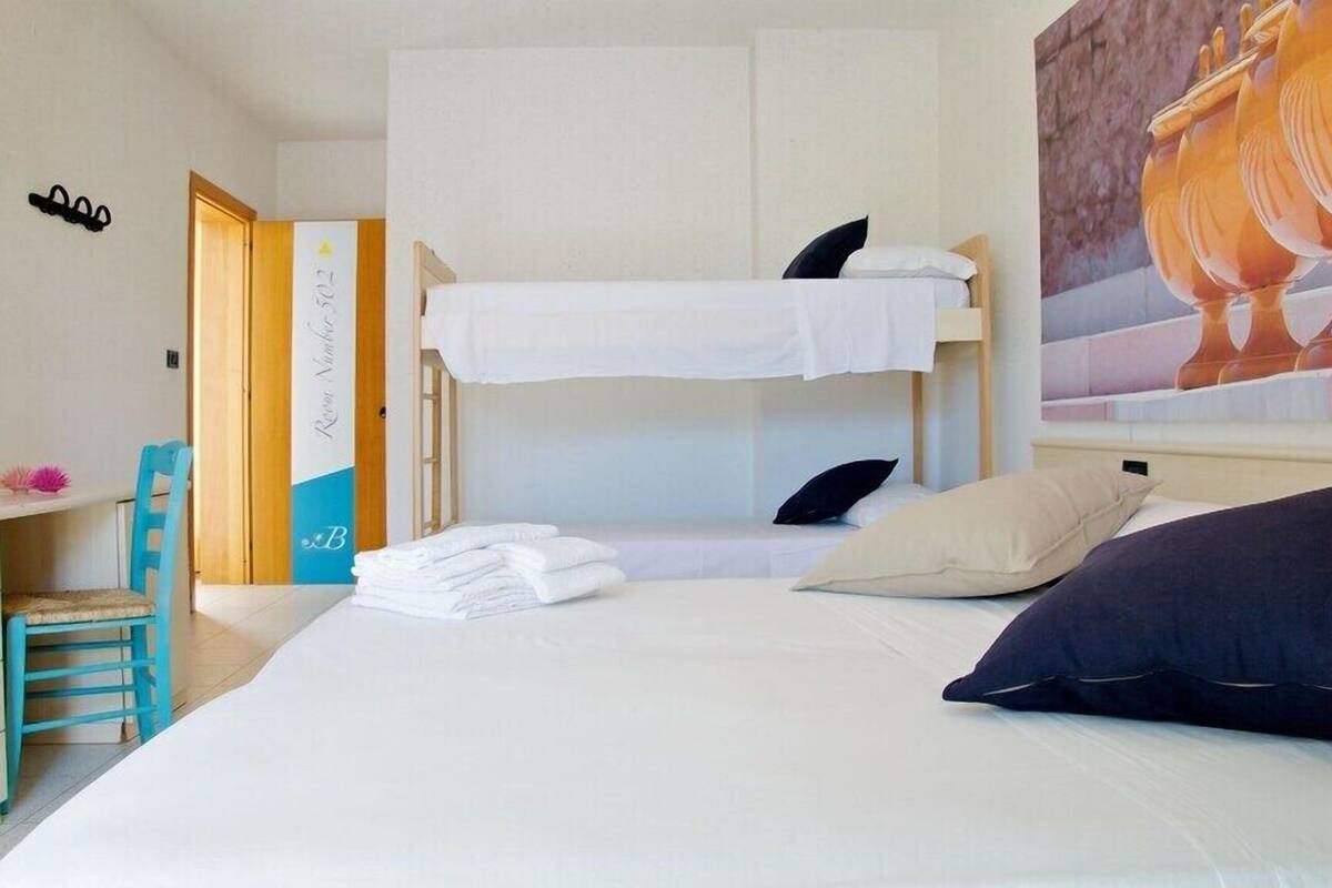 Ein Hotelzimmer mit einem Etagenbett, einem Schreibtisch mit Stuhl und einem Bild an der Wand.
