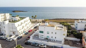 Une zone résidentielle côtière avec des bâtiments blancs, une route et une plage en arrière-plan.