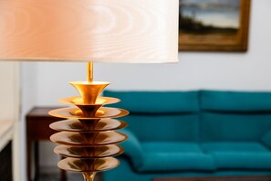 Een moderne lamp met een uniek spiraalvormig ontwerp, een blauwgroene bank en een ingelijst kunstwerk aan de muur.