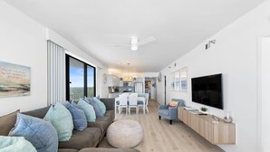 Ein modernes Wohnzimmer mit einem braunen Sofa, einem runden Hocker und einem Fernseher auf einem Holzboden.