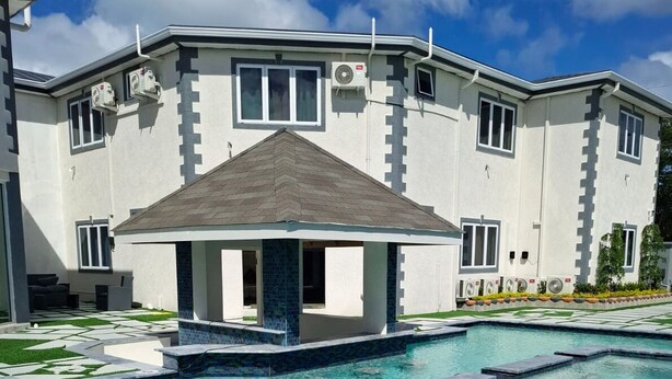 Un edificio moderno con piscina, patio coperto e giardino curato.