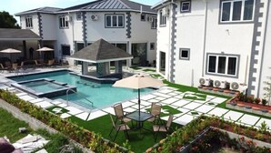 Una proprietà residenziale con piscina, mobili da patio e un gazebo coperto.