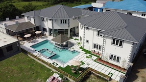 Un'ampia casa moderna con piscina, diverse terrazze e un giardino curato.