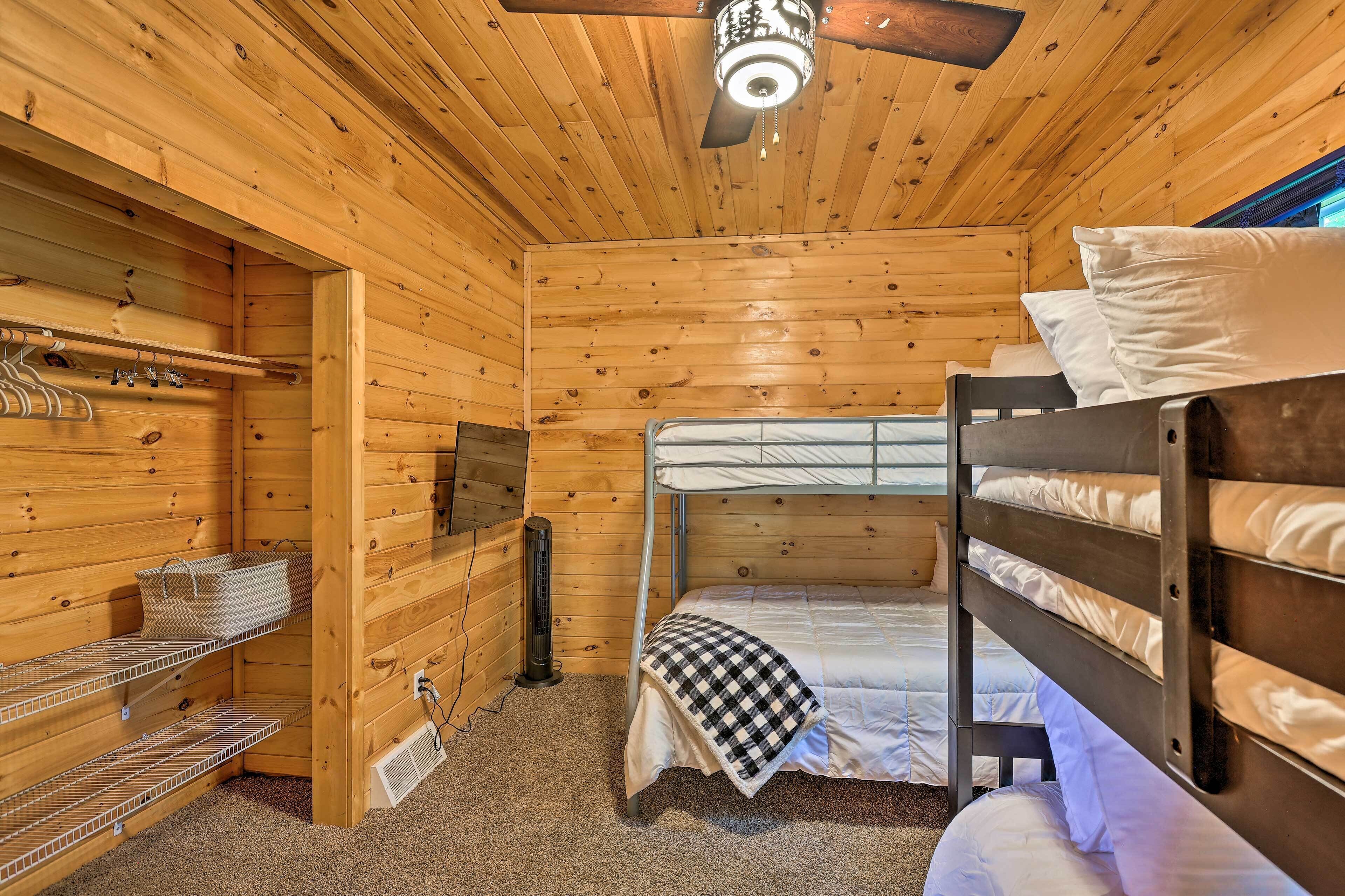 Une chambre rustique en bois avec des lits superposés, un ventilateur de plafond et un radiateur fixé au mur.