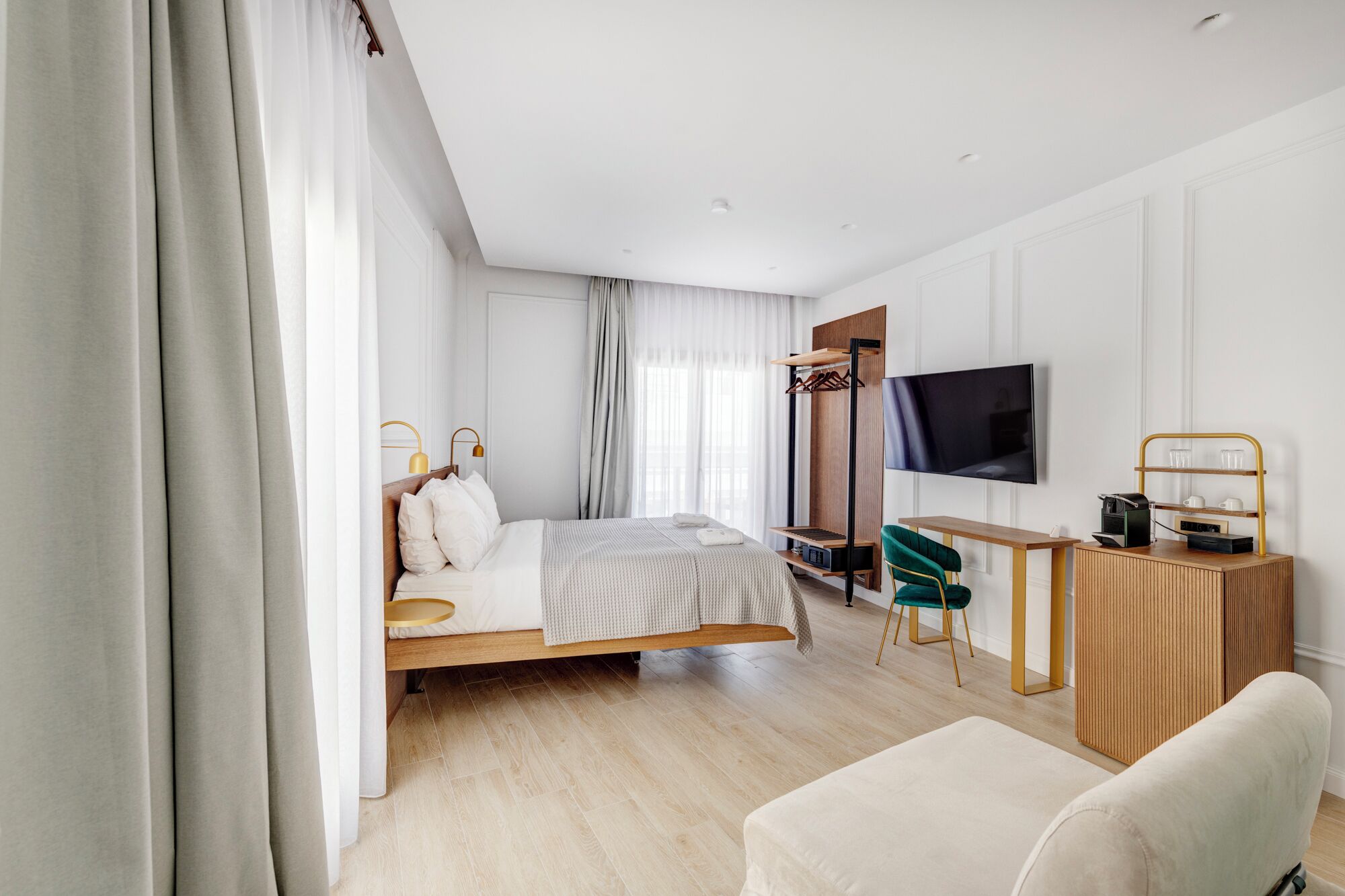 A modern hotel room with a bed, a desk, a TV, and a chair.