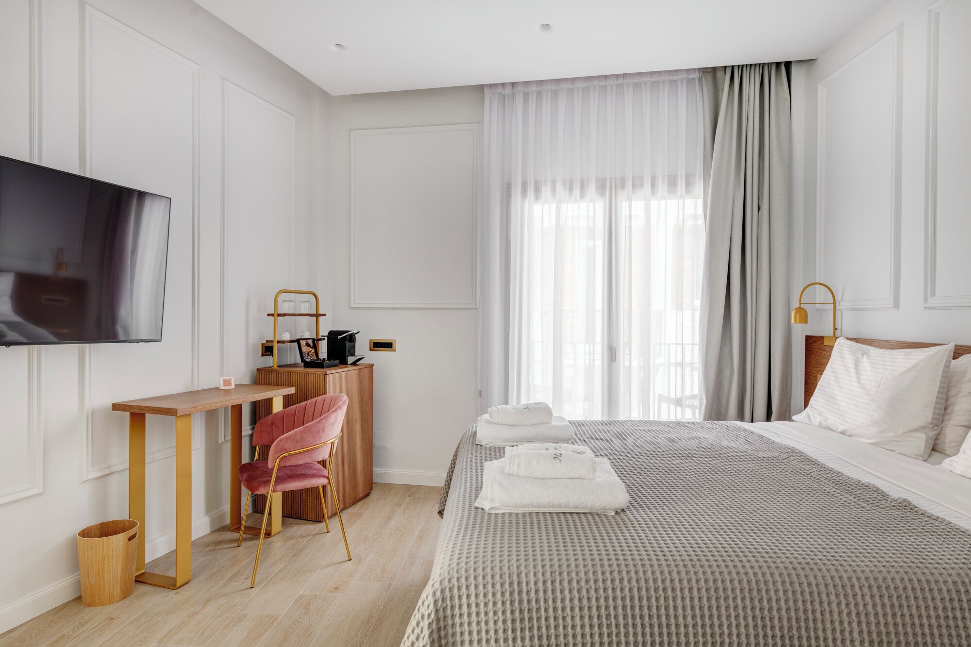 A hotel room with a bed, a desk, a chair, a television, and a window with curtains.