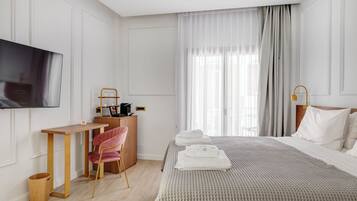 A hotel room with a bed, a desk, a chair, a television, and a window with curtains.