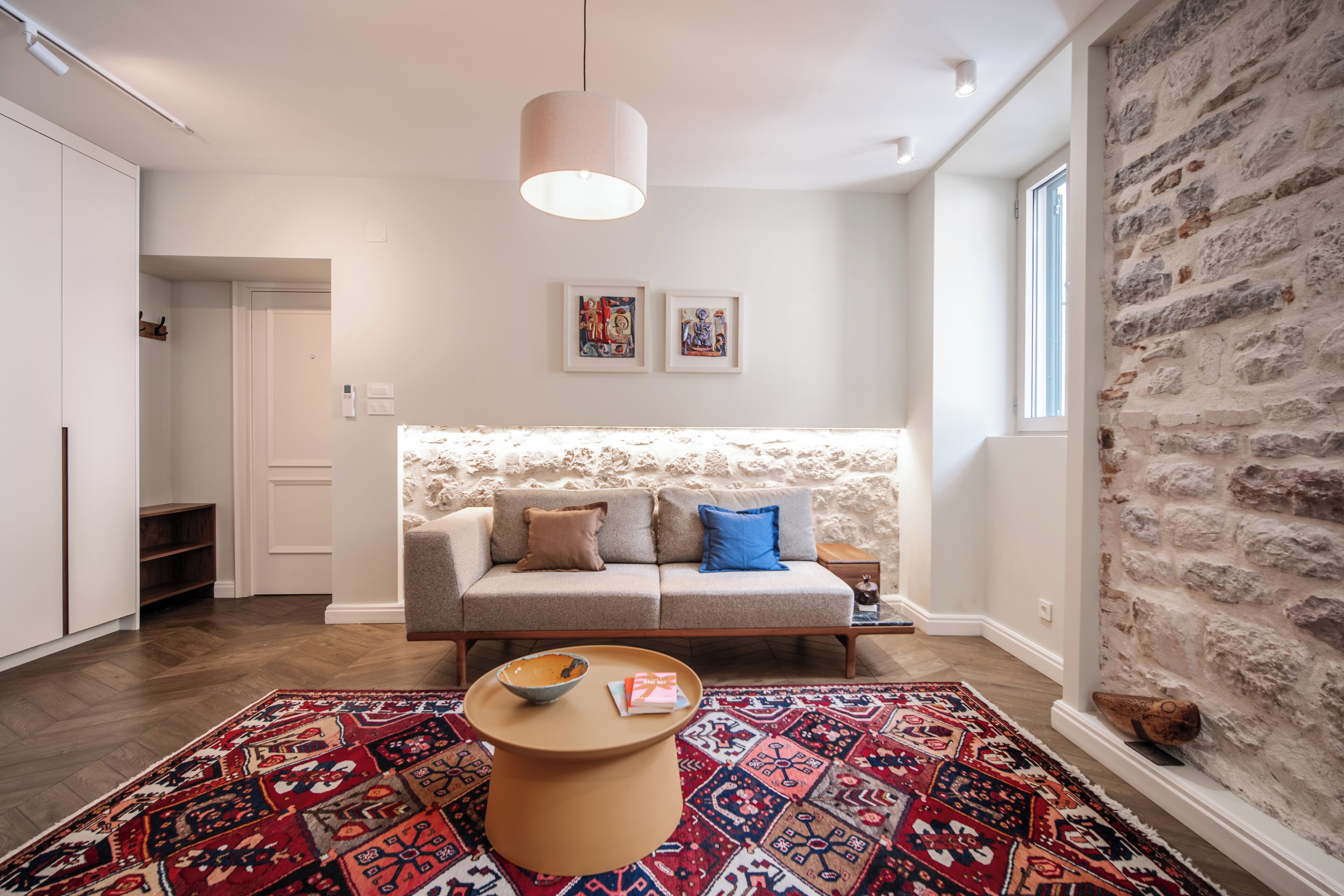Ein modernes Wohnzimmer mit einer Couch, einem Couchtisch und einem gemusterten Teppich.