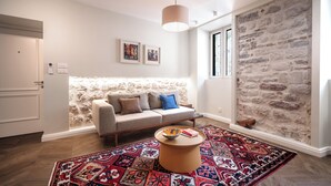 Un salon moderne avec un mur d’accent en pierre, un canapé avec des coussins, une table basse et un tapis à motifs.