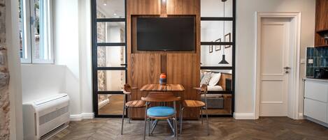 Una cocina moderna con televisor integrado, piso de madera y zona de comedor con sillas.
