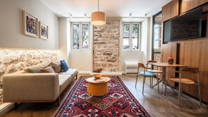 Un salon moderne avec un mur en pierre, un canapé, une table basse et un téléviseur fixé au mur.