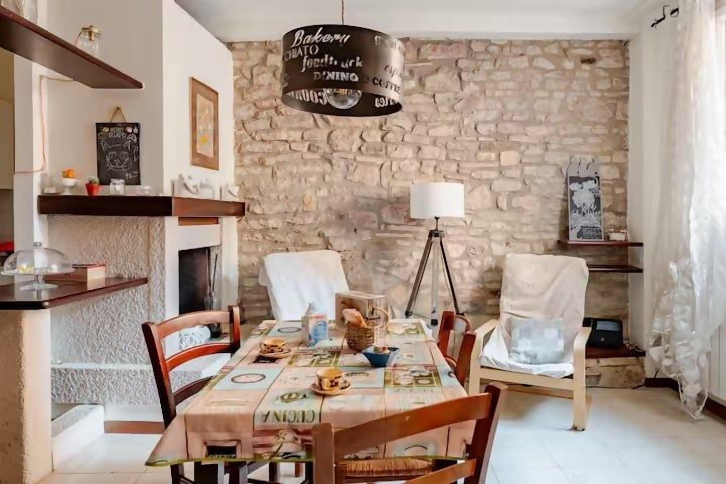 A dining area with a stone wall, a table set with plates, and chairs.