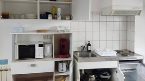 A compact kitchen with white cabinetry, a microwave, a toaster, a coffee maker, and a sink. - Le Faubourg (Saint-Quentin)
