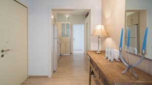 A hallway with a wooden bench, a lamp, and a mirror with blue candle holders.