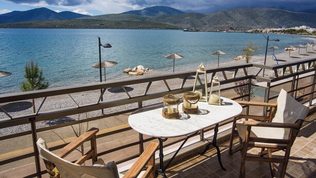 A terrace with a table and chairs overlooking a lake with mountains in the background.
