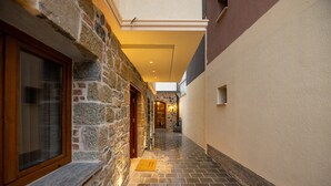 Un estrecho pasillo con paredes de piedra, una puerta de madera y un piso de baldosas que conduce a una escalera.