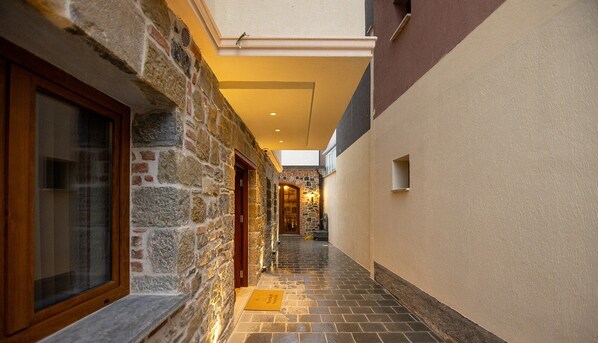 A narrow corridor with stone walls, a wooden door, and a tiled floor leading to a staircase. - "Moonlight Serenade" - Entire Villa in the historic center of Korça. (Korçë)