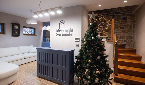 A reception area with a Christmas tree, a blue reception desk, a staircase, and a stone wall.