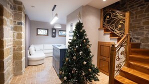 Una sala de estar acogedora con un sofá blanco, un árbol de Navidad y una escalera con barandillas ornamentadas.