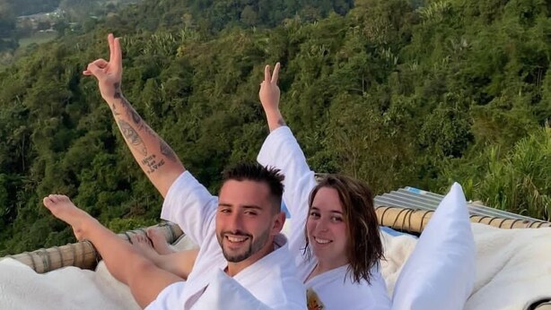 Una pareja descansando en una hamaca con una vista panorámica de las montañas al fondo.
