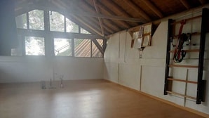 Una habitación amplia con piso de madera, ventanas grandes y una pared de escalada.