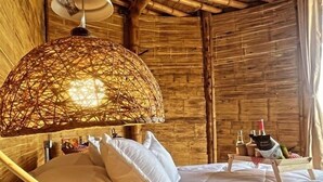 Una habitación rústica de madera con una cama, una lámpara y una pequeña mesa con botellas.
