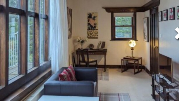 Un salon chaleureux avec un plafond en bois foncé, un canapé, une petite table et une fenêtre avec des rideaux.