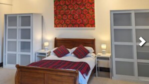 Une chambre à coucher avec un lit en bois, une décoration murale rouge à motifs et une armoire blanche.