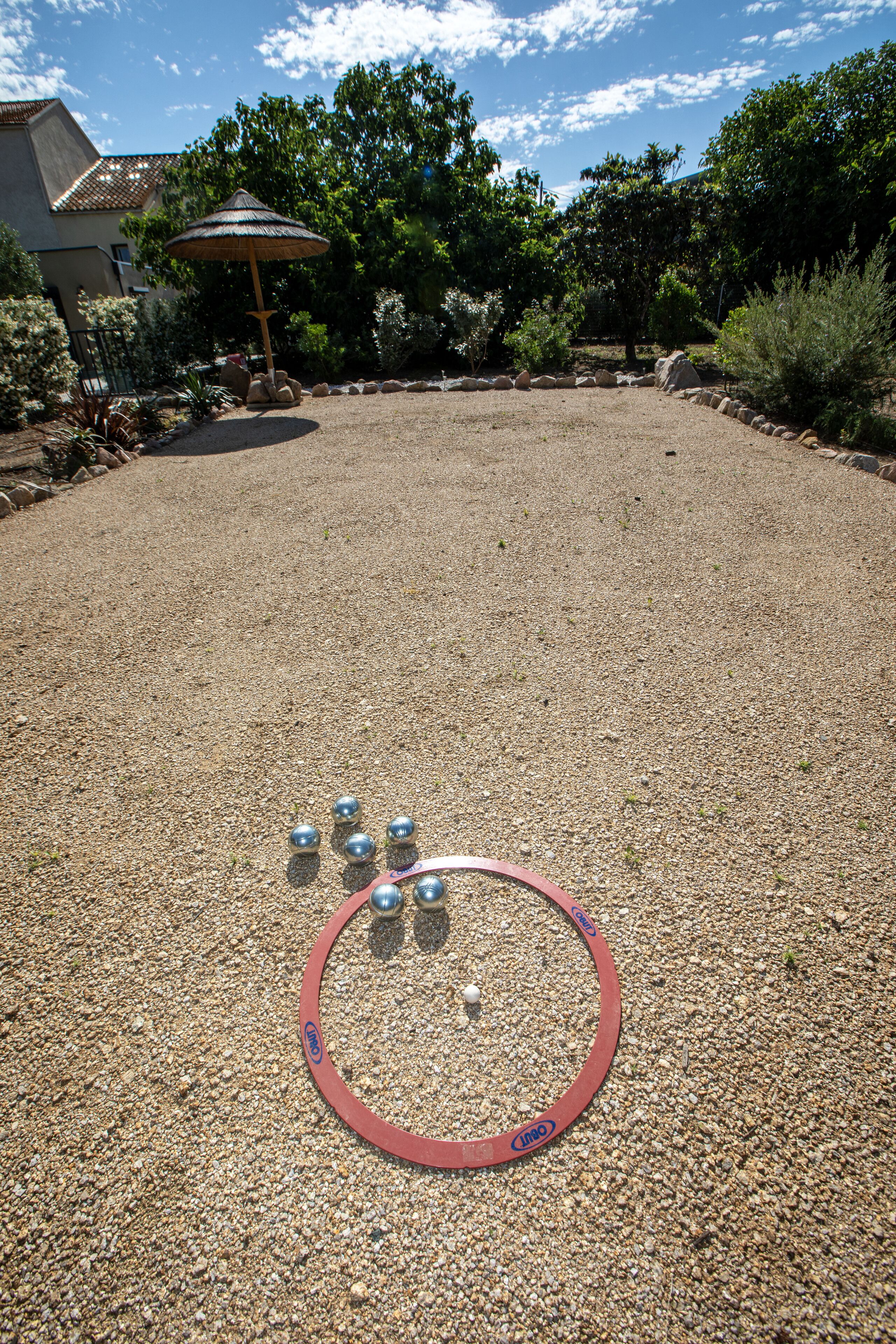 A gravel patio with a hula hoop and metal balls.