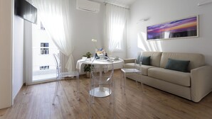 A modern living room with a beige sofa, a round table, and clear chairs. - Ca' Benedetta Suite House Apartsuite Chioggia (Chioggia)