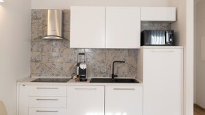A modern kitchen with white cabinets, a built-in microwave, a coffee maker, and a gas stove. - Ca' Benedetta Suite House Apartsuite Chioggia (Chioggia)