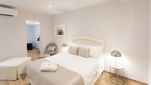 A modern bedroom with a large bed, bedside tables, a chair, and a lamp. - Ca' Benedetta Suite House Apartsuite Chioggia (Chioggia)