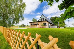 A wooden fence in a grassy area with a building in the background. - Luxurious vacation home in the countryside in the Zittauer Gebirge Nature Park (Hainewalde)