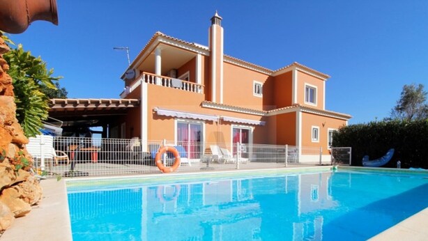 A two-story house with a swimming pool in front.