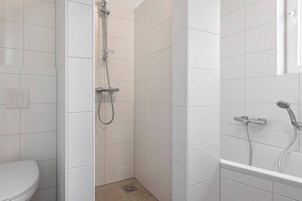 Een kleine, witte badkamer met toilet, douche en bad.