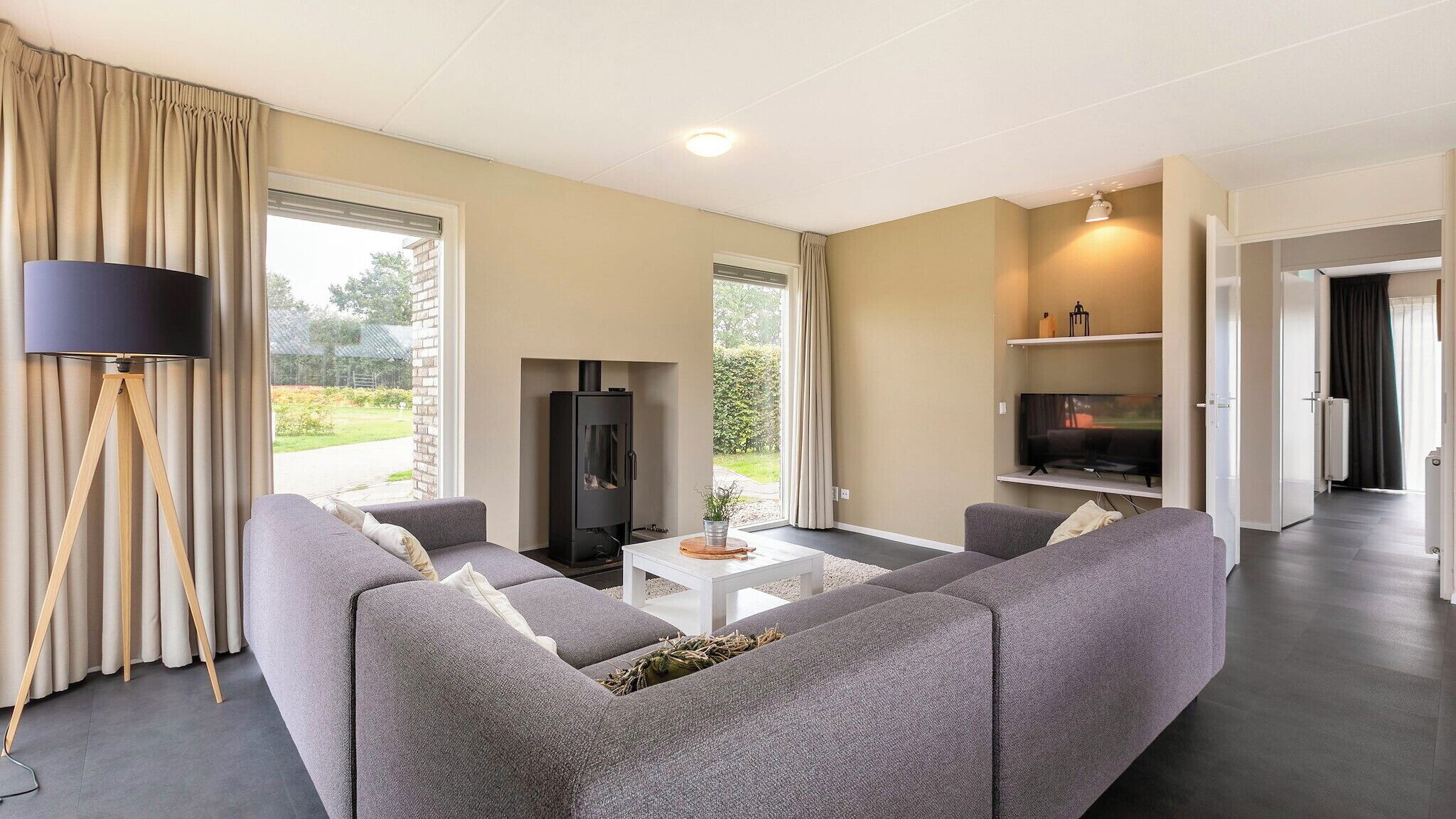 A modern living room with a grey sofa set, a coffee table, a floor lamp, a fireplace, and a TV.