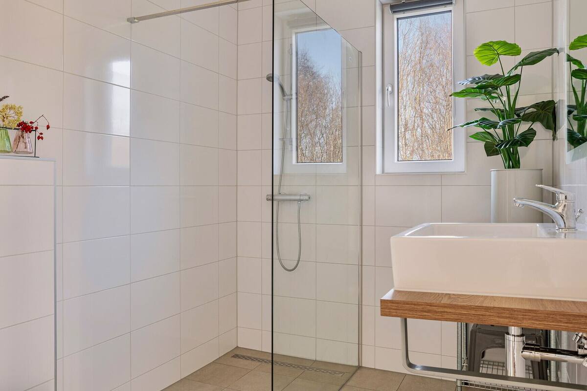Een moderne badkamer met een douchecabine van glas, een wastafel met houten blad en potplanten.
