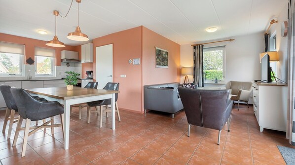 A modern kitchen with a dining area, a sofa, and a TV. - Summio Villapark Akenveen (Tynaarlo)
