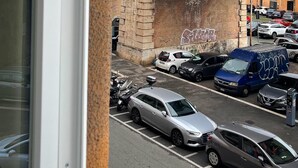 A street view with a historic stone bridge, a domed building in the background, and parked cars. - Ele rooms San Pietro (Rome)