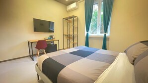 A hotel room with a bed, a desk, a chair, a TV, a wardrobe, and a window with curtains. - Ele rooms San Pietro (Rome)