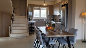 Une cuisine moderne avec un coin repas, des appareils électroménagers en acier inoxydable et un escalier.