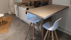 A compact kitchen with a central island, two bar stools, a microwave, and a built-in oven.