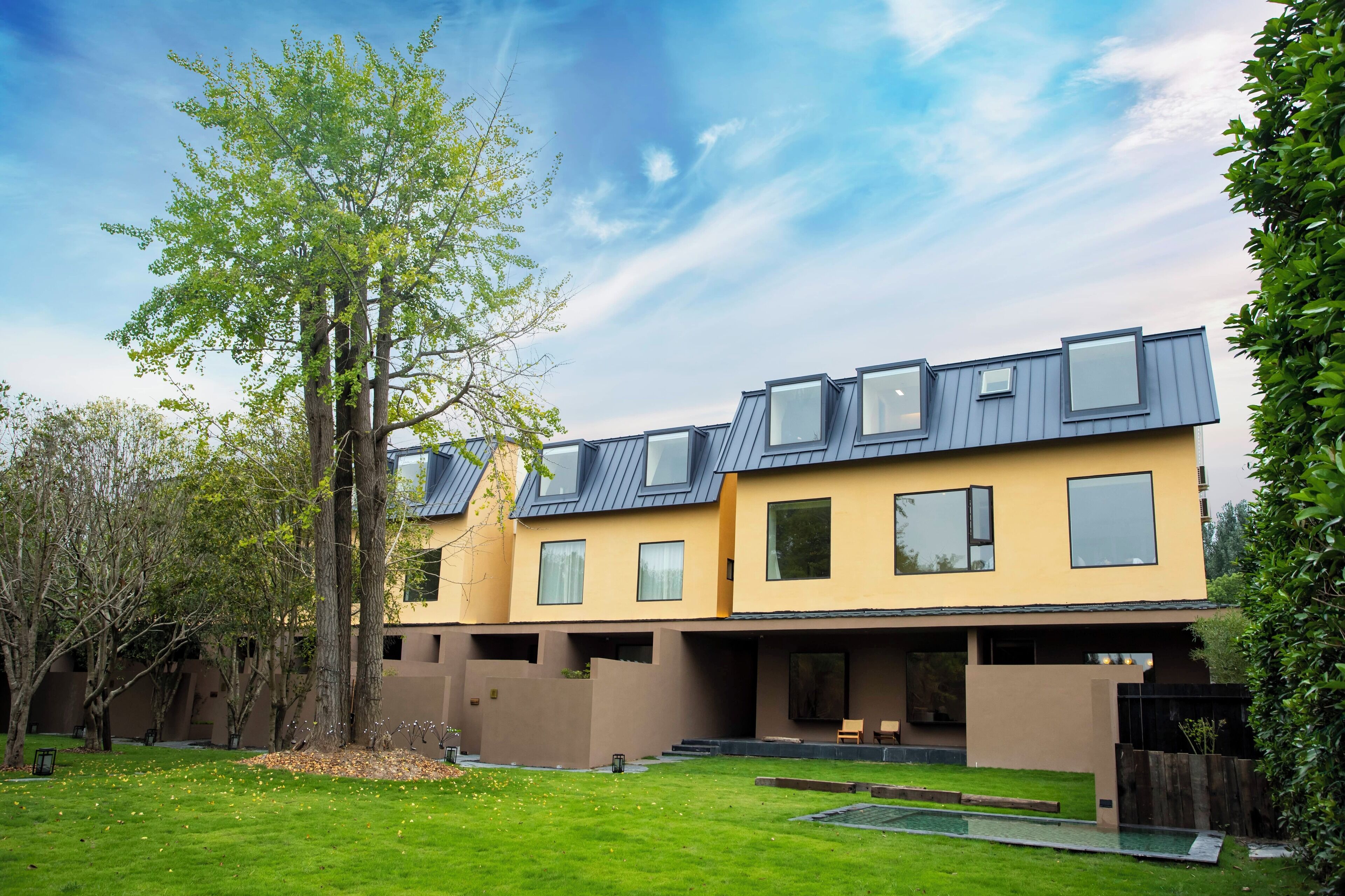 A modern two-story house with a flat roof, large windows, and a well-maintained lawn.