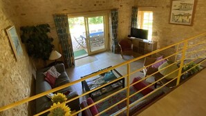 A rustic living room with a sofa, a coffee table, and a television. There is a staircase with a railing leading to an upper level. - Beautiful house with heated pool. Quiet location, close to attractions. (Bouzic)