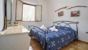 A bedroom with a bed, a bedside table, a mirror, and a window. - Dimora Del Mare - Villa With Garden Near The Sea (Porto Cesareo)