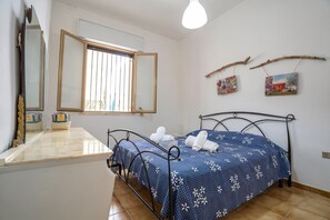 Ein Schlafzimmer mit Bett, Nachttisch, Spiegel und Fenster.