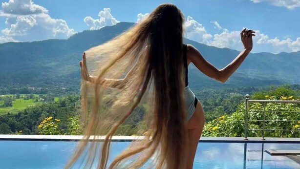 Une personne se tient près d’une piscine, avec un paysage montagneux en arrière-plan.