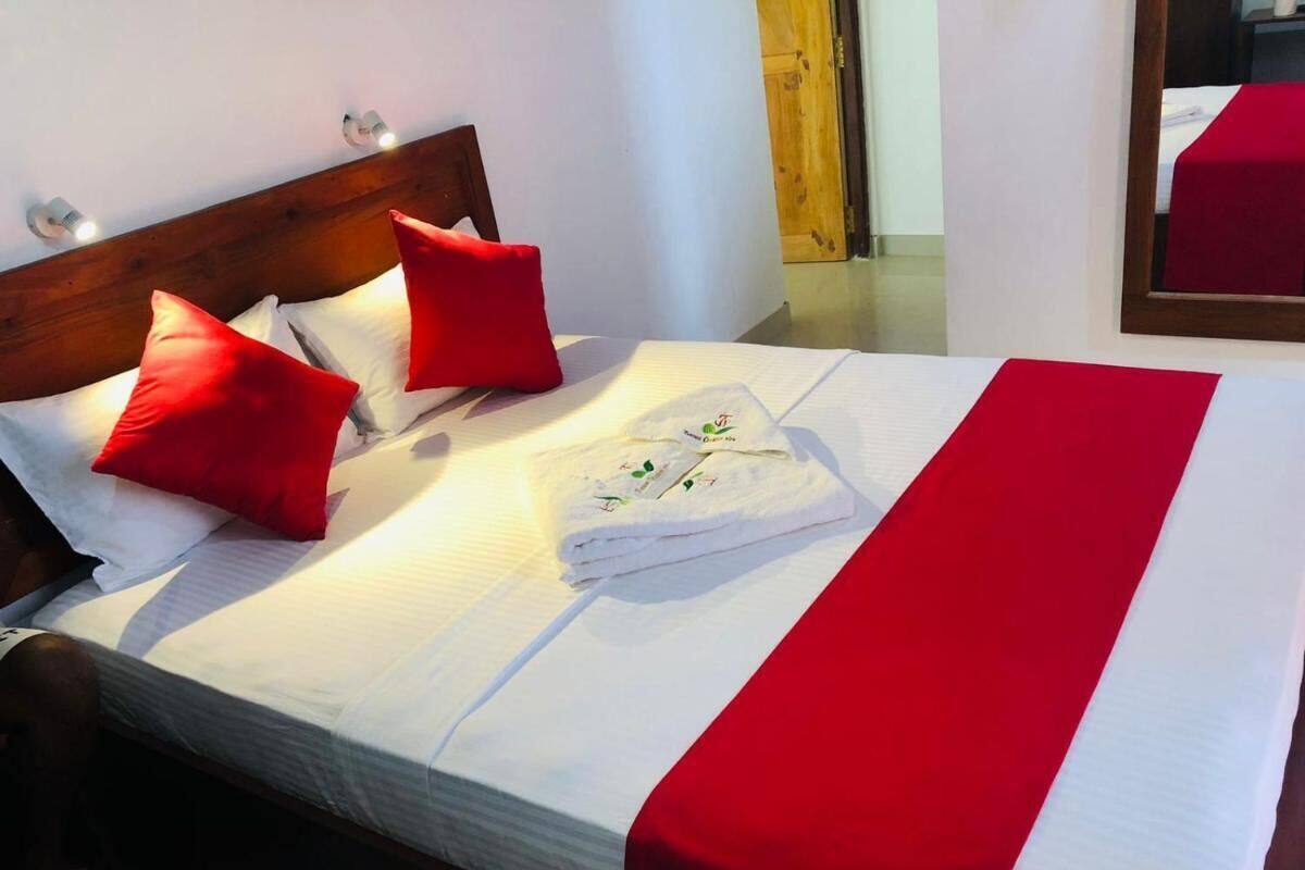 Una cama bien hecha con almohadas rojas, una toalla blanca y una colcha roja.